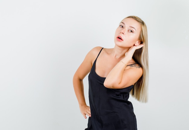 Young female in black singlet trying to hear something confidential and looking serious 