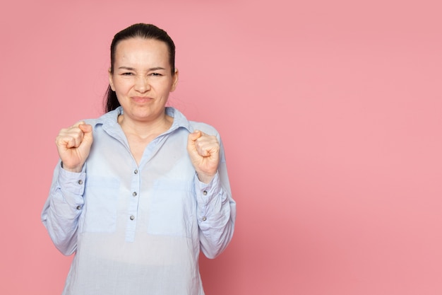 Free photo young female in blue shirt posing on the pink wall