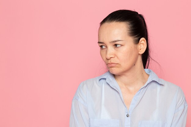 young female in blue shirt posing on the pink wall