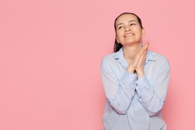 young female in blue shirt posing on the pink wall