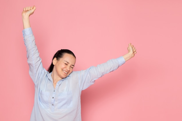 Giovane femmina in camicia blu in posa sul muro rosa