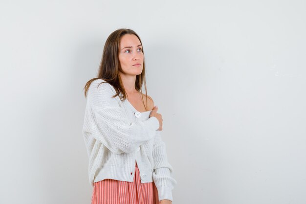 Young female in cardigan and skirt posing while looking away looking elegant isolated