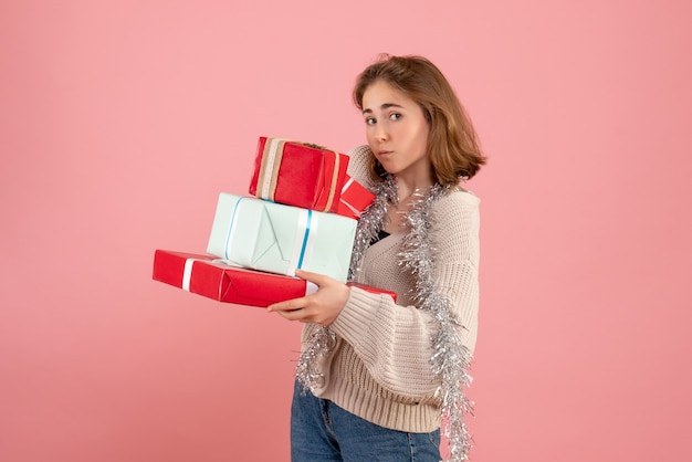 young female carrying xmas presents on pink