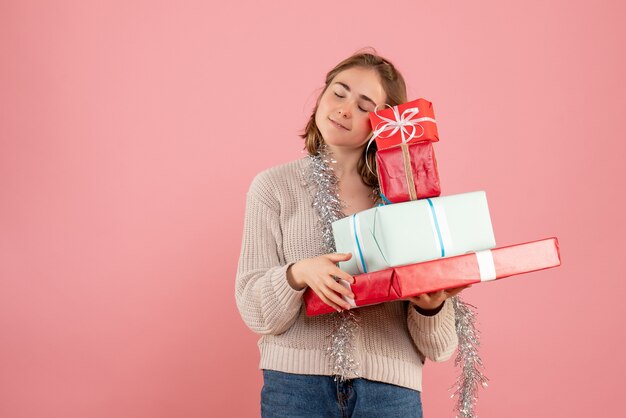 ピンクのクリスマスプレゼントを運ぶ若い女性