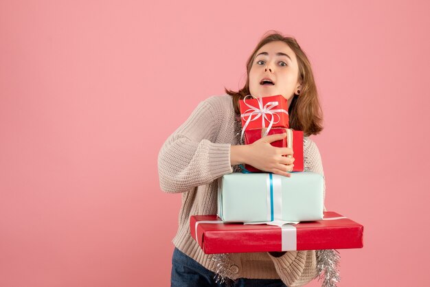 young female carrying xmas presents on pink