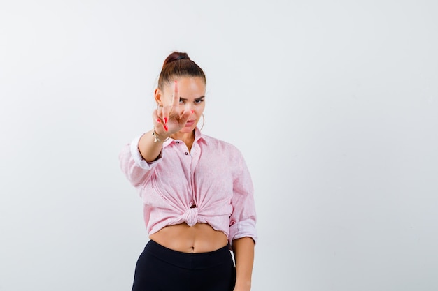 Giovane donna in camicia casual che mostra tenere un gesto minuto e guardando fiducioso, vista frontale.