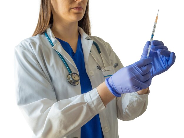 Young female caucasian doctor in a medical uniform and gloves preparing the syringe for an injection