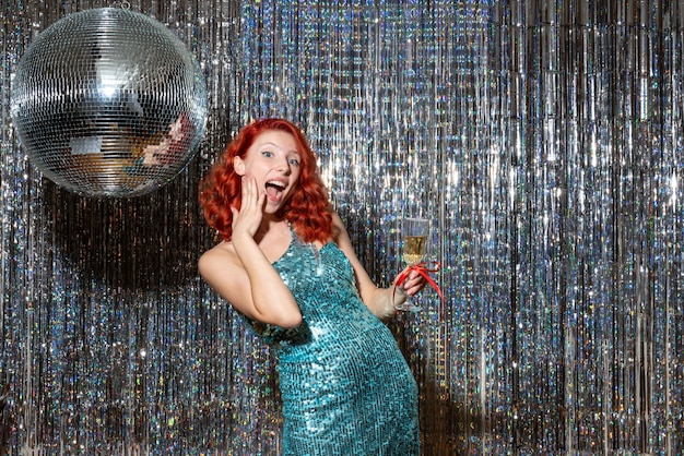 young female celebrating new year in party in beautiful dress on bright curtains