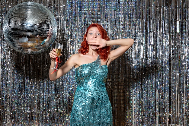 молодая женщина празднует новый год в вечеринке с диско-шаром на ярких шторах