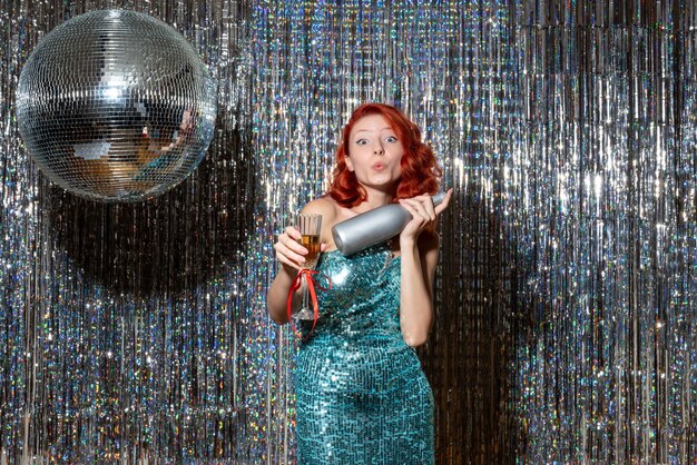 young female celebrating new year with champagne in party on shiny curtains