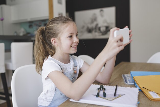 Young female child video calling a friend and smiling from home