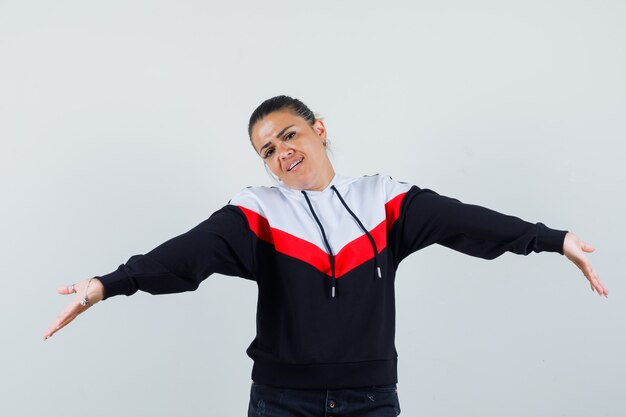 Young female in colorful sweatshirt showing helpless gesture and looking hopeless , front view.