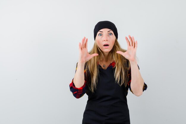 Young female cook in a black apron being scared