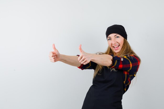 Young female cook in a black apron showing thumbs up