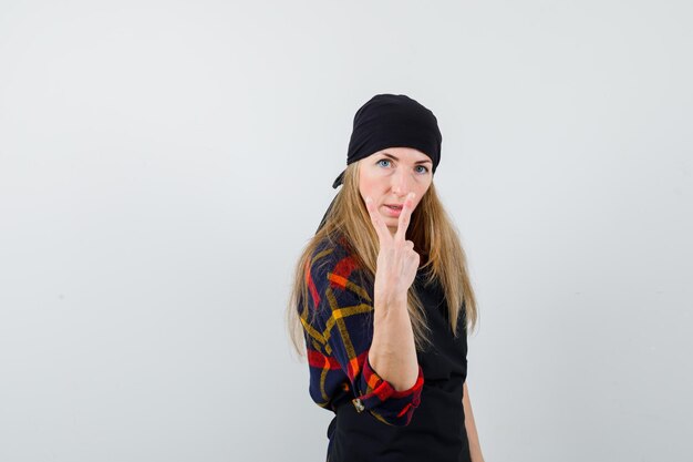 Young female cook in a black apron showing victory sign