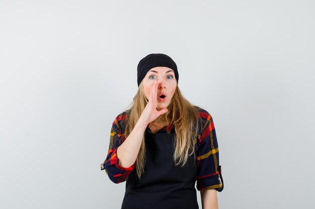 Young female cook in a black apron whispering