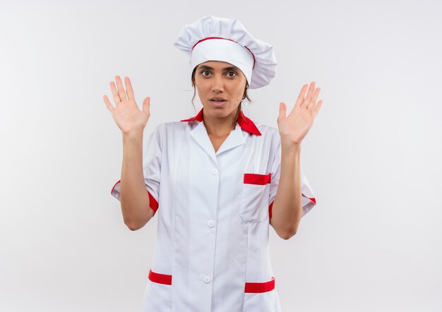 young female cook wearing chef uniform raising hands on isolated white wall with copy space