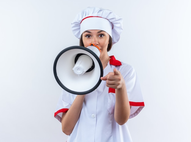 Young female cook wearing chef uniform speaks on loudspeaker isolated on white background