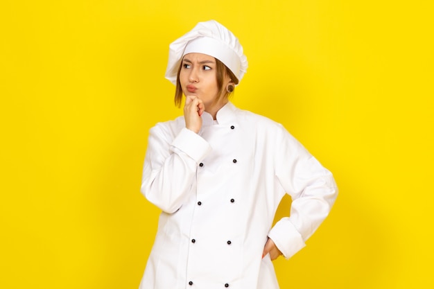 若い女性の白いクックスーツと白い帽子思考式で調理