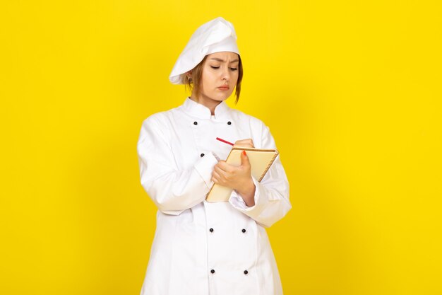 흰색 쿡 슈트와 흰색 모자 메모를 작성하는 젊은 여성 요리