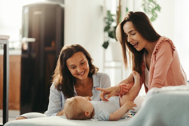 赤ちゃんの息子と遊んで、家で楽しんでいる若い女性のカップル