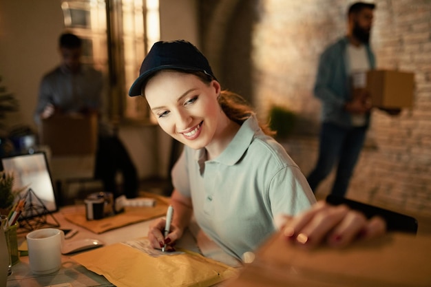 Young female courier checking to see if the addresses match while preparing packages for a delivery in the office