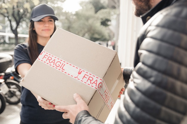 Young female courier delivering package to man