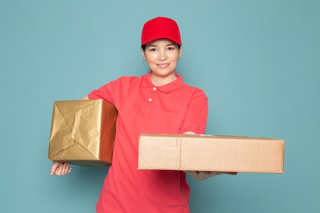 파란색 벽에 분홍색 티셔츠 빨간 모자 들고 상자에 젊은 여성 택배