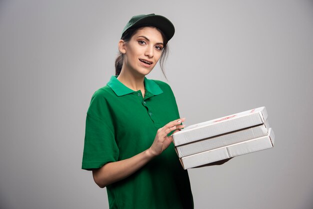 Молодая женщина-курьер позирует с коробками для пиццы