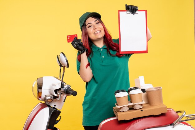 young female courier with delivery coffee and food on yellow