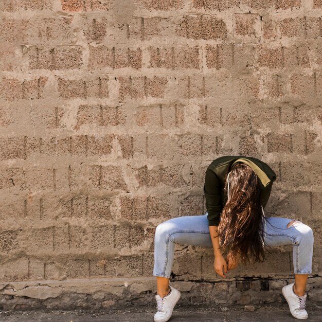 Young female dancer posing in front of wall