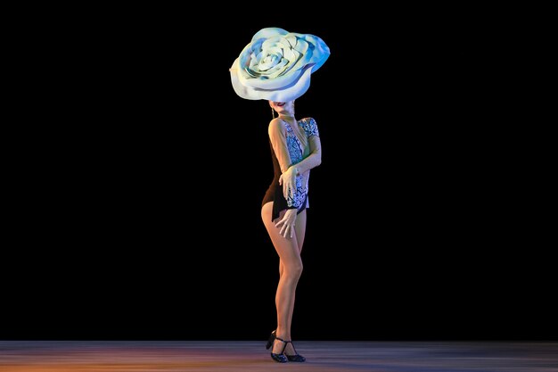 검은 벽에 네온 불빛에 거대한 꽃 모자와 젊은 여성 댄서