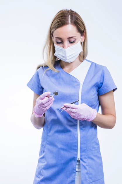 Young female dentist holding forceps and dental mirror