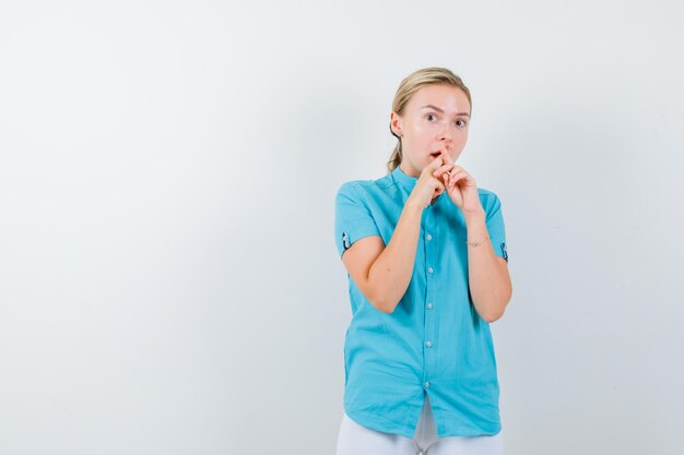 Young female doctor holding crossed fingers near mouth in medical uniform