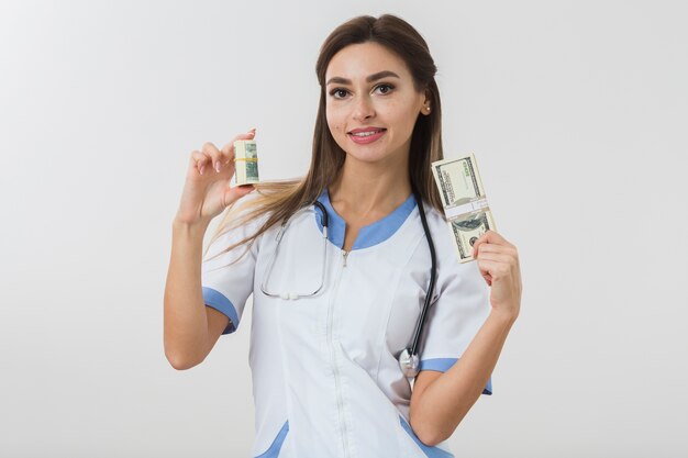 Молодая женщина-врач держит деньги