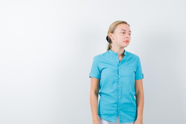 Young female doctor looking away in medical uniform, mask and looking pensive