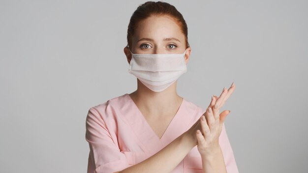 白い背景の上のカメラで手を洗う医療マスクの若い女性医師安全第一概念
