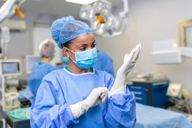 若い女性医師が手術の準備をしますコートとマスクに青い手術用手袋を着用します