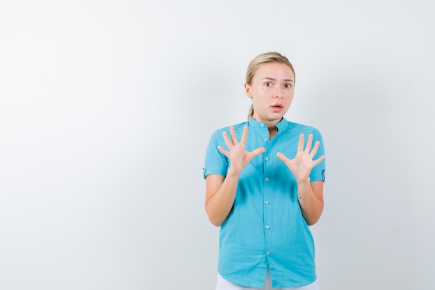 Young female doctor showing palms in surrender gesture in medical uniform