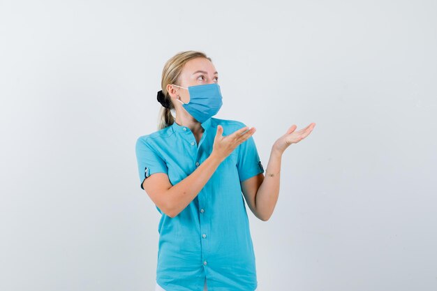 Young female doctor showing something in uniform and looking puzzled