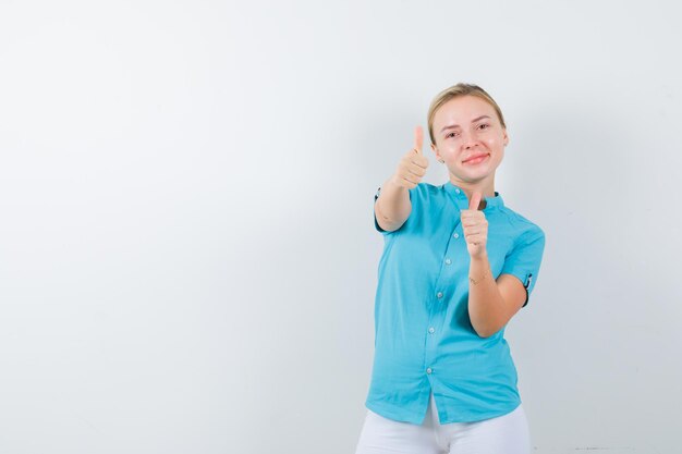 Young female doctor showing thumbs up in medical uniform, mask and looking positive