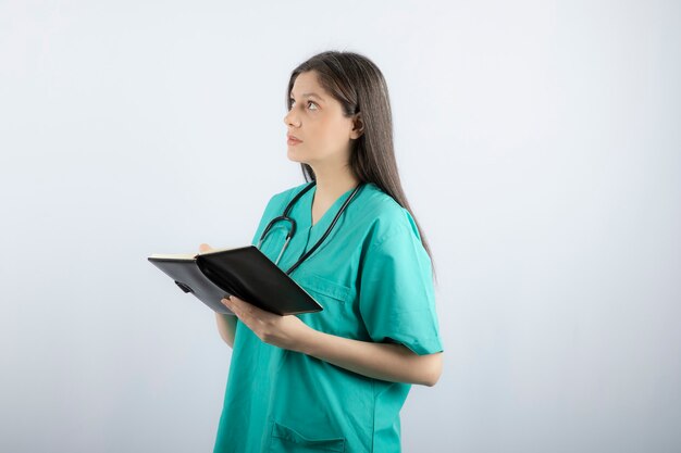 노트북과 연필로 서 있는 젊은 여성 의사.