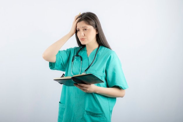 young female doctor standing with notebook and pencil. 