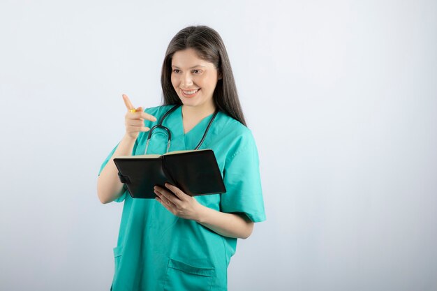 young female doctor standing with notebook and pencil. 