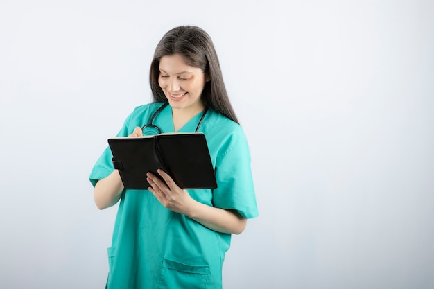 young female doctor standing with notebook and pencil. 