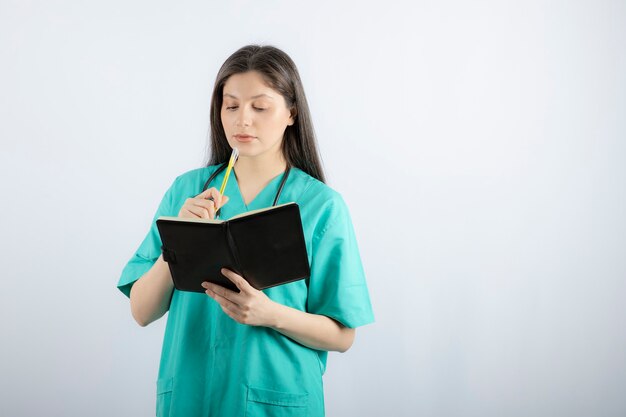 young female doctor standing with notebook and pencil. 