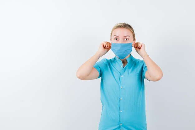 Young female doctor in uniform pulling earlobes with fingers isolated