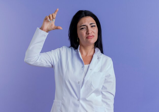 Young female doctor wearing medical robe looking showing amount gesture 