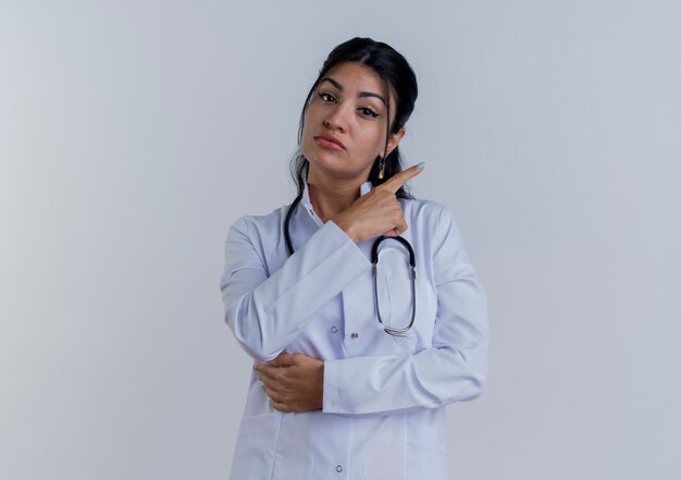 Молодая женщина-врач в медицинском халате и стетоскопе смотрит на изолированную сторону