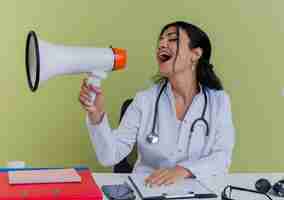 Free photo young female doctor wearing medical robe and stethoscope sitting at desk